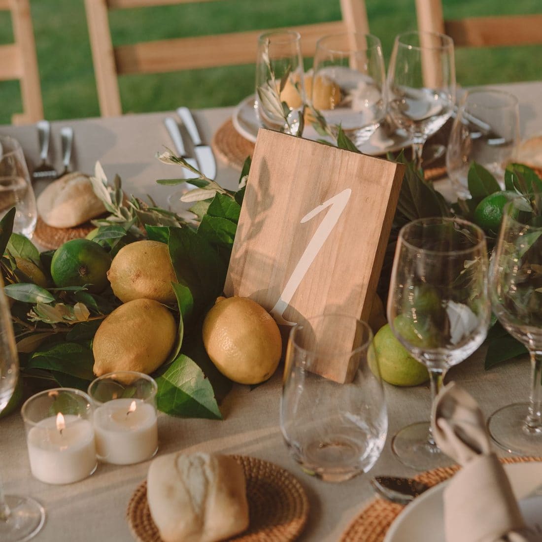 Centre de taula amb llimones, fulles verdes i número de taula de fusta en un banquet de casament