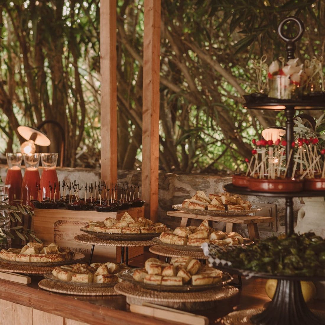 Bufet d’aperitius amb pastes salades i broquetes en safates de vímet en un casament a l’aire lliure