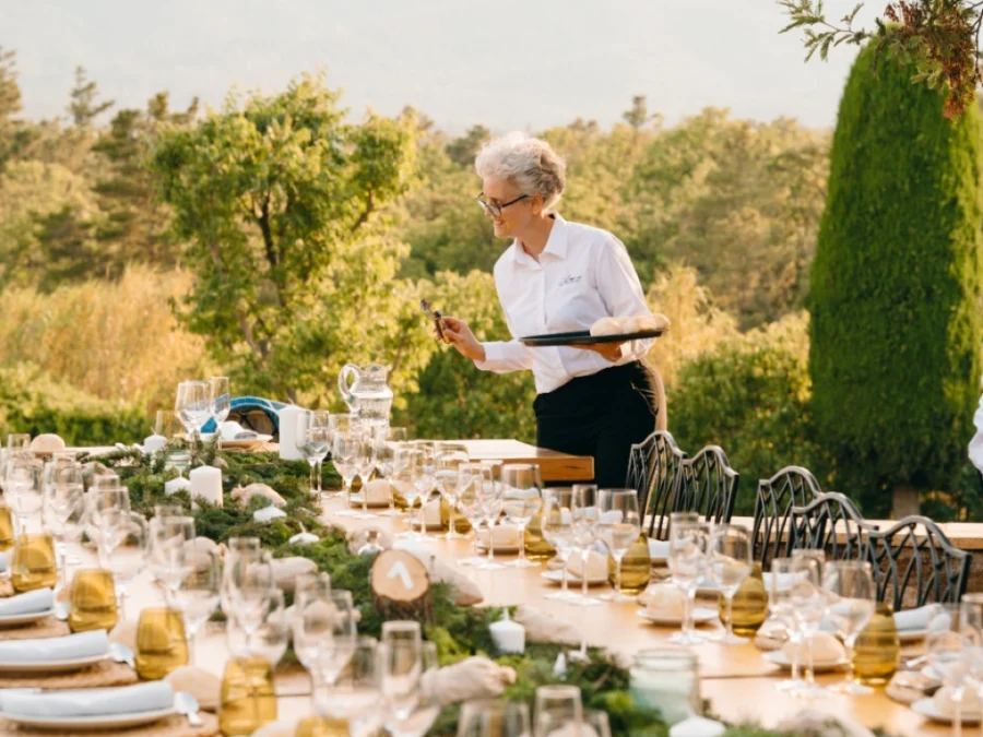 Server with a tray setting a long table with mountains behind