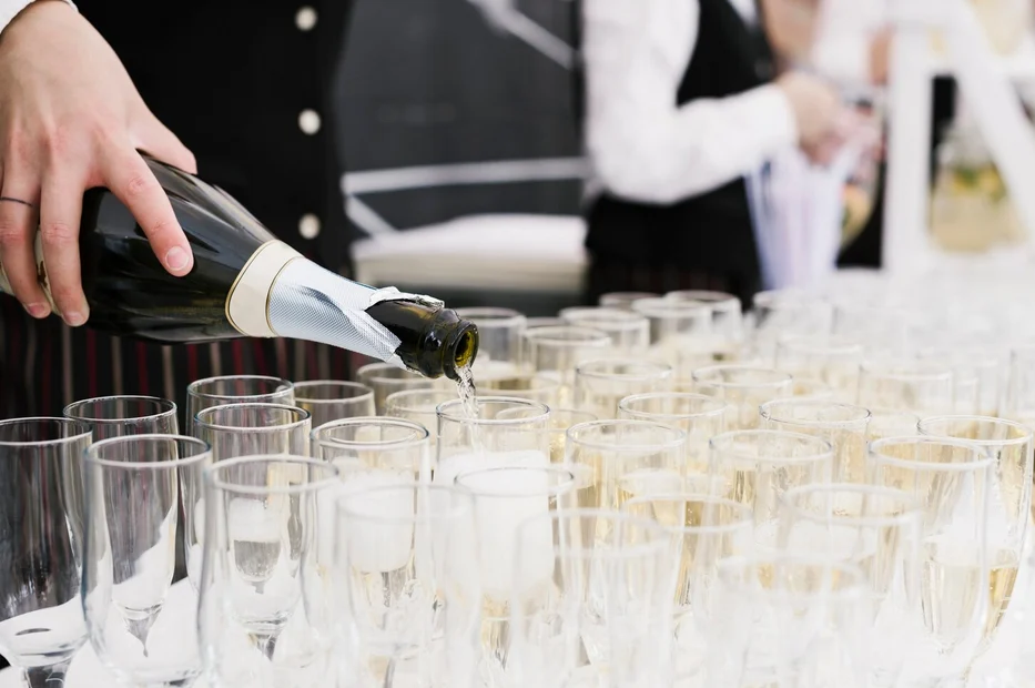Camarero llenando filas de copas de cava con una botella