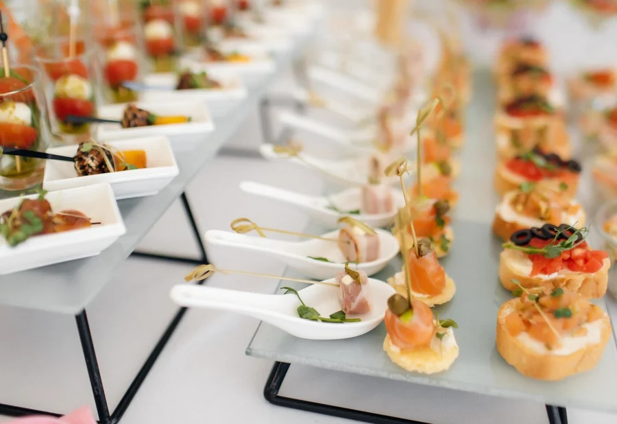 Rows of canapés and white spoons with ham, salmon and small toasts