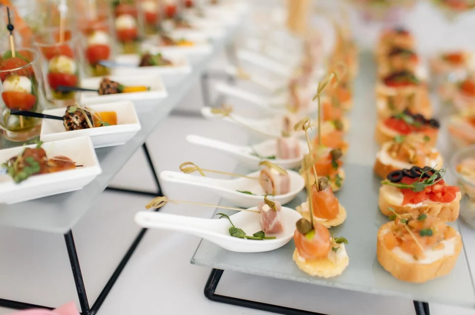 Rows of canapés and white spoons with ham, salmon and small toasts