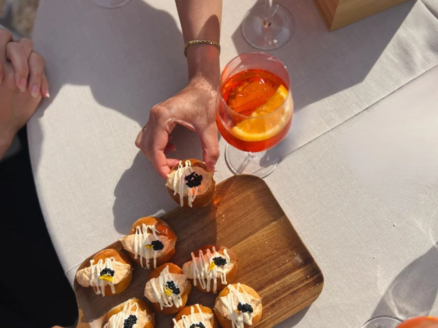 Mans agafant una lionesa amb caviar d'una taula amb còctels taronges