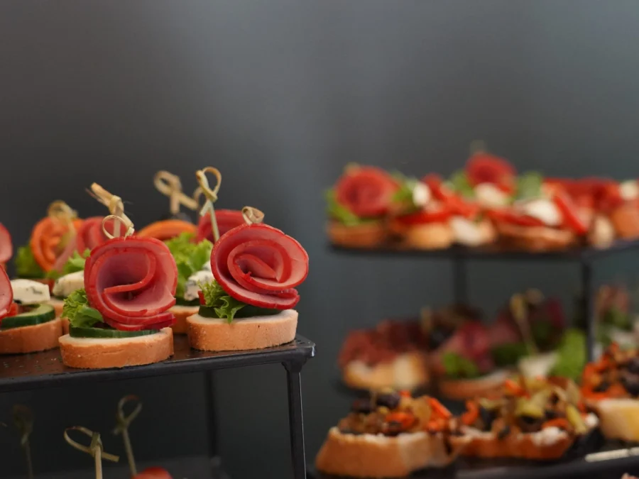 Canapés en expositores negros con embutido enrollado, tomate y lechuga