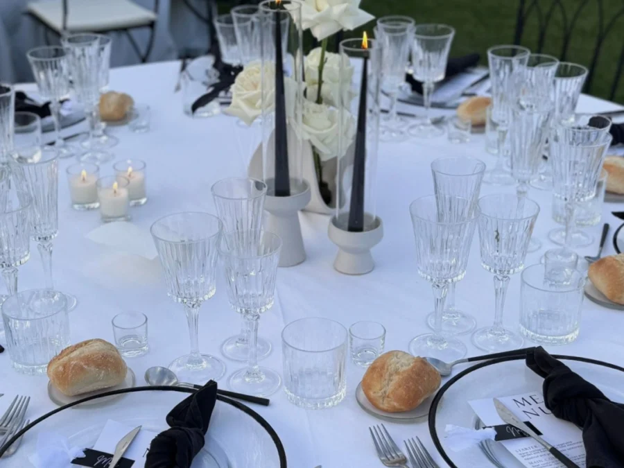 Mesa redonda con rosas blancas, velas negras, servilletas negras y panecillos