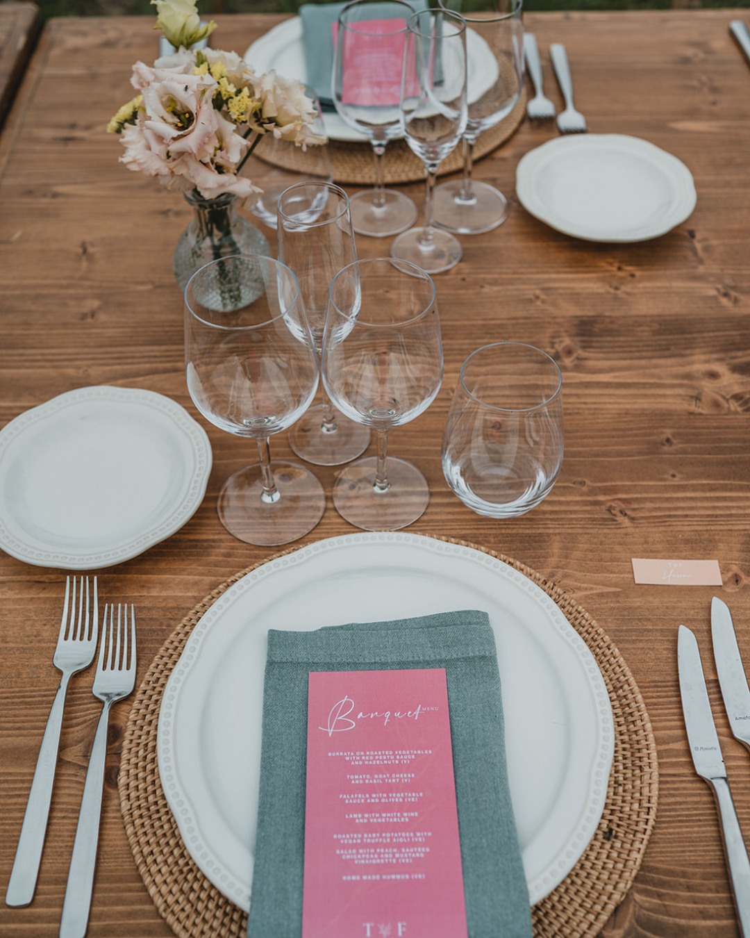 Parament sobre fusta amb plat blanc, tovalló verd i menú rosa