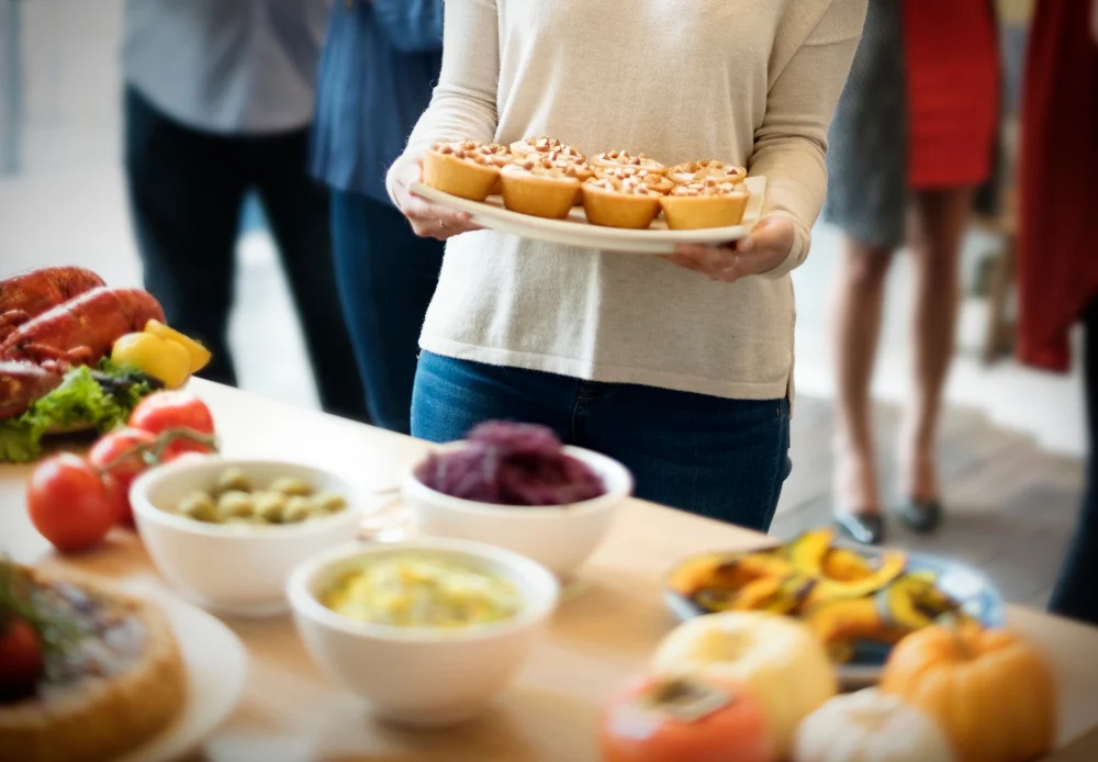 Dona servint una safata de pastissets davant d'un bufet amb bols i verdures