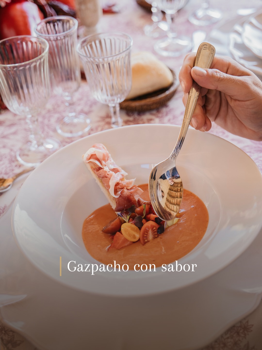 Plato de sopa fría de tomate con tomates cherry y un rollito de jamón