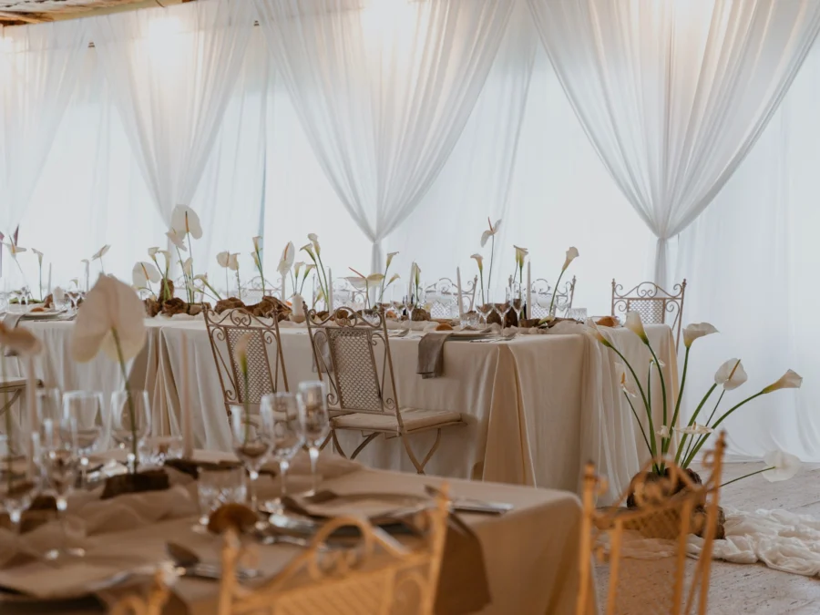 Carpa amb cortines blanques, taules en tons beix i centres de flors blanques