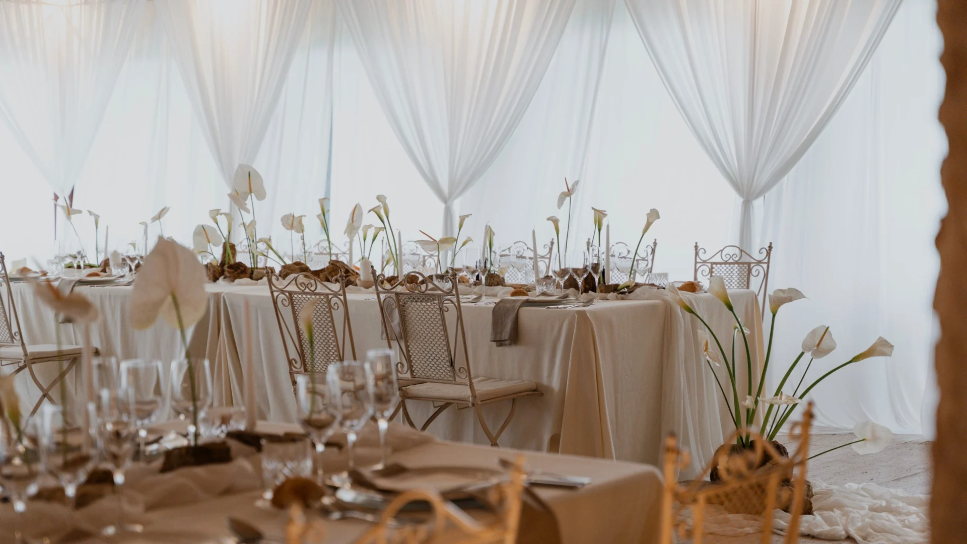 Draped white marquee with beige-linen tables and white flower centrepieces